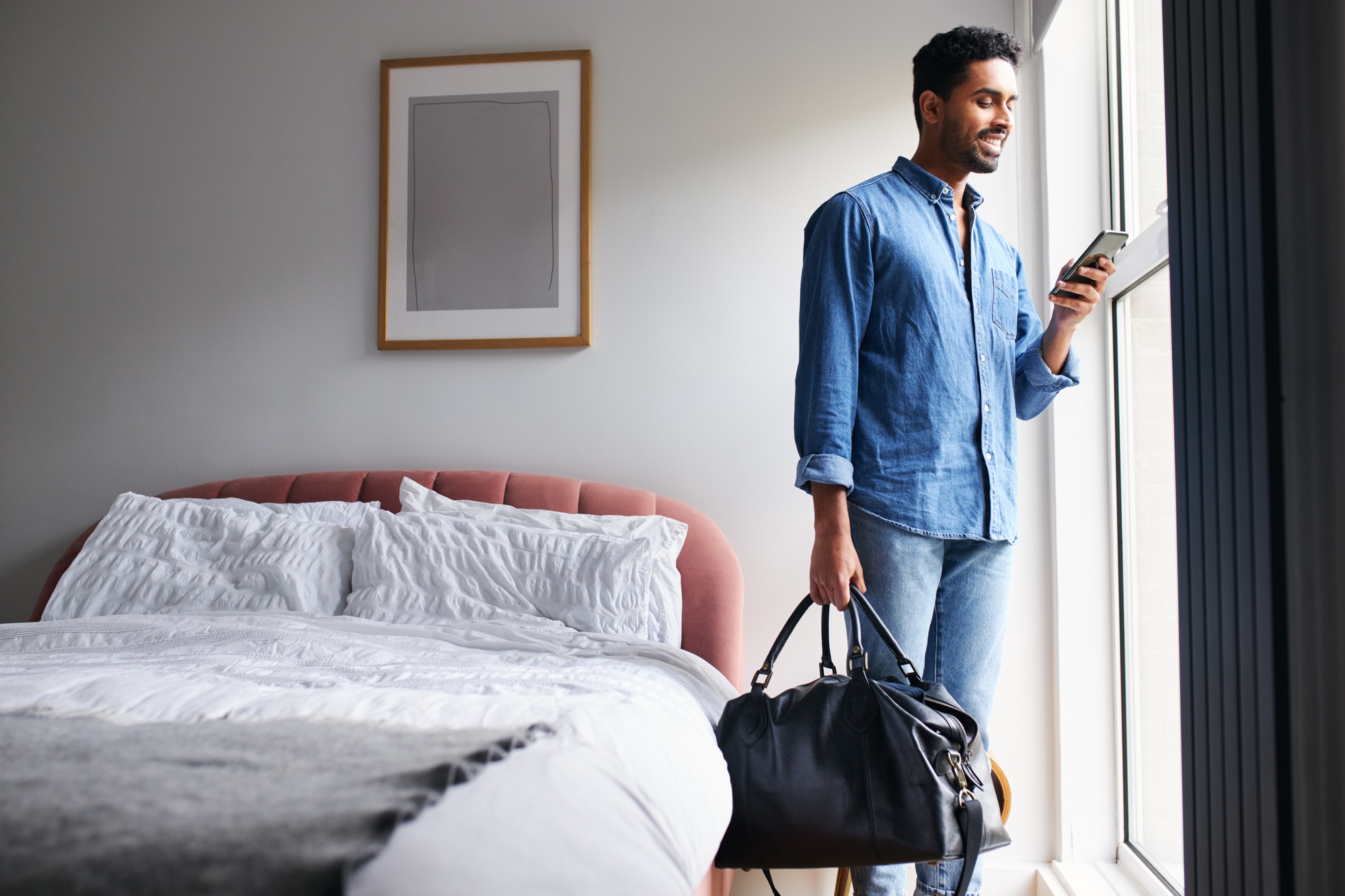 Man Staying In Boutique Hotel Checking Emails And Social Media In Room
