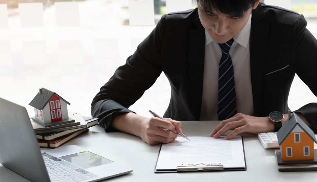 Real estate agent with house model hand putting signing contract,have a contract in place to protect