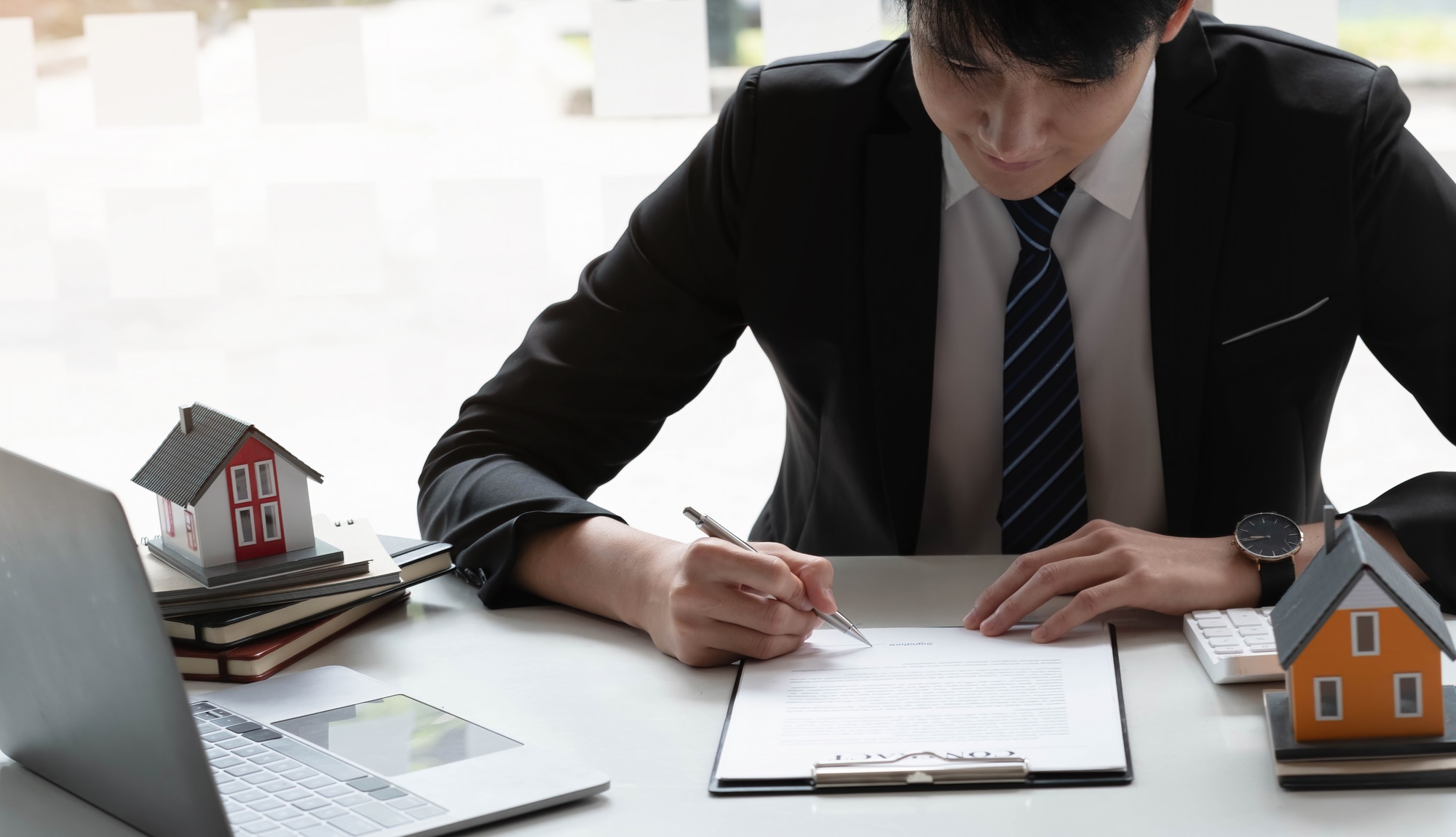 Real estate agent with house model hand putting signing contract,have a contract in place to protect